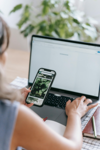 distracted economy - girl looking at phone while sitting with laptop open