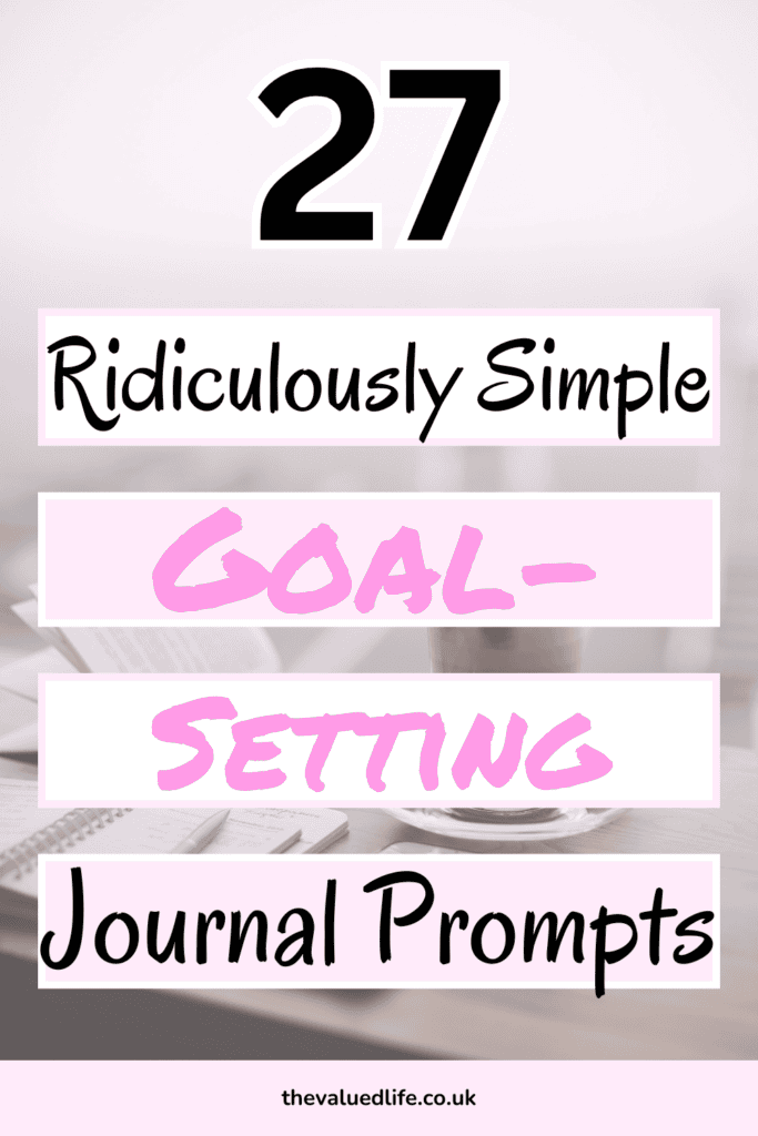 text '27 Ridiculously Simple Goal-Setting Journal Prompts' in bold and pastel pink and black fonts, set against a blurred background of a desk with an open journal, pen, and coffee cup.