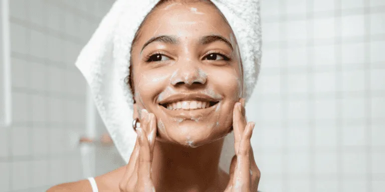 Woman washing her face with a towel wrapped around her hair to symbolise a guilt-free self-care day