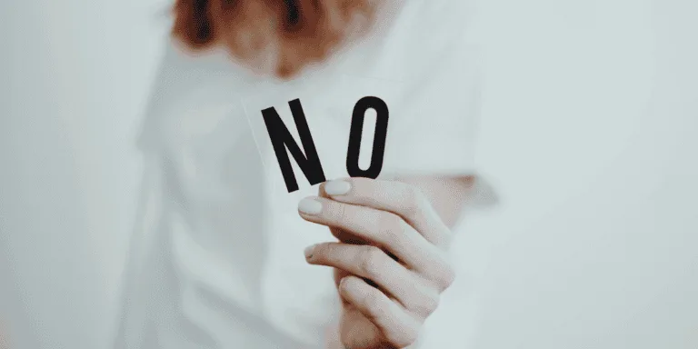 A woman holding up the letters 'N' and 'O'. Boundaries for perfectionists