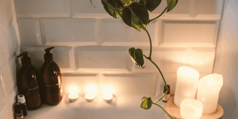 A relaxing setting in the bathroom: lit candles, bath bottles, and a plant to symbolise protecting peace and energy