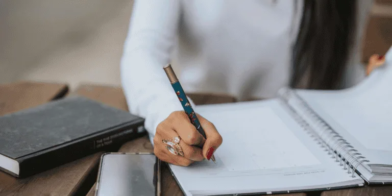 a woman writing in an open notebook - 54321 goal-setting