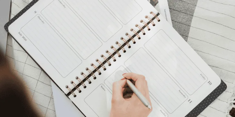 Open notebook with a hand holding a pen on top - mindful action plan