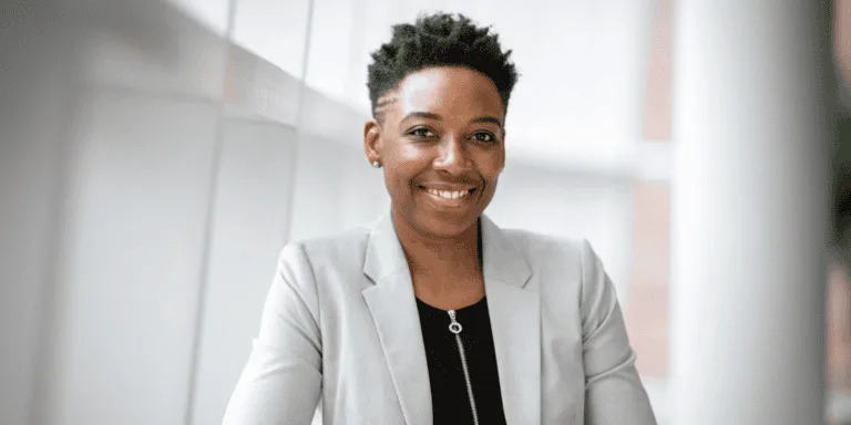 a smiling woman wearing a grey suit jacket and a black top - values-driven mindset