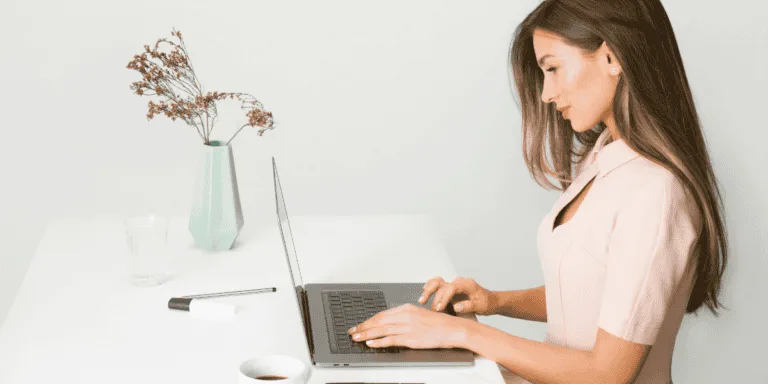 Woman in Pink Dress Using Laptop Computer to symbolise how to be anti-hustle culture and productive