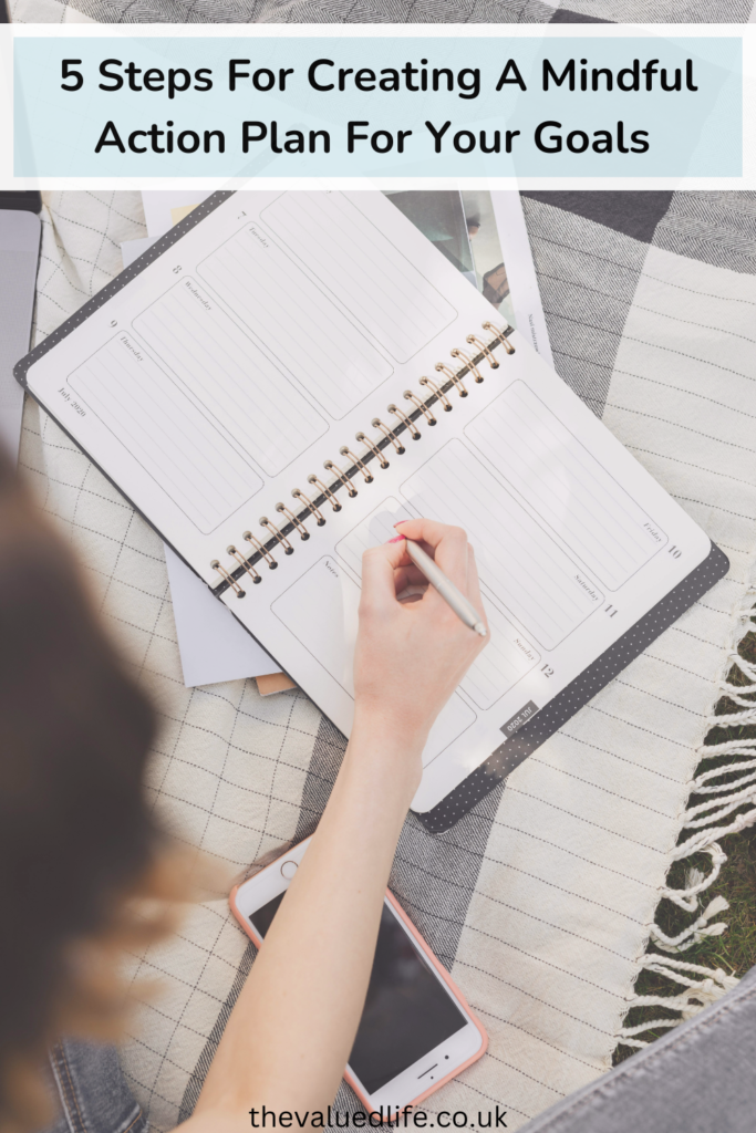 open notebook with a persons hand holding a pen on top of it. Text overlay that says 5 steps for creating a mindful action plan for your goals