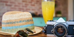 Gray and Black Dslr Camera Beside Sun Hat and Sunglasses to symbolise summer affirmations for good vibes