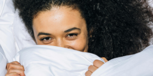 closeup of a woman's face holding on to a white duvet as part of a realistic evening routine