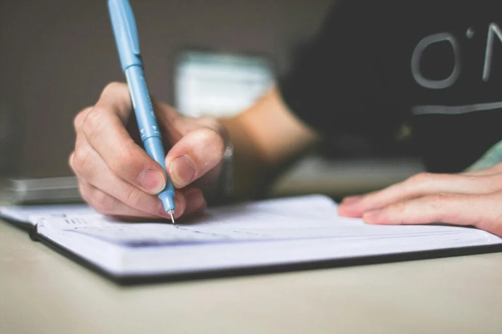 a person writing in an open notebook to write down your vision and create a purpose statement