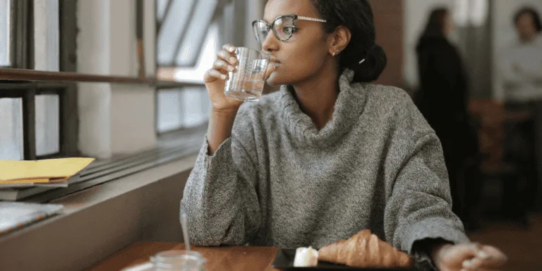 Woman In Gray Sweater drinking in a coffee shop by herself as a self-care solo dates