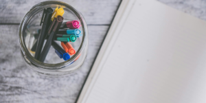 Clear Glass Jar Filled of Coloring Pens Beside of an open bullet journal to show how long a bullet journal lasts