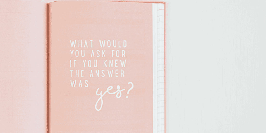 Open journal with the prompt 'What would you ask for if you knew the answer was yes?' written on a soft pink page, ideal for inspiring reflection and new year journal prompts.