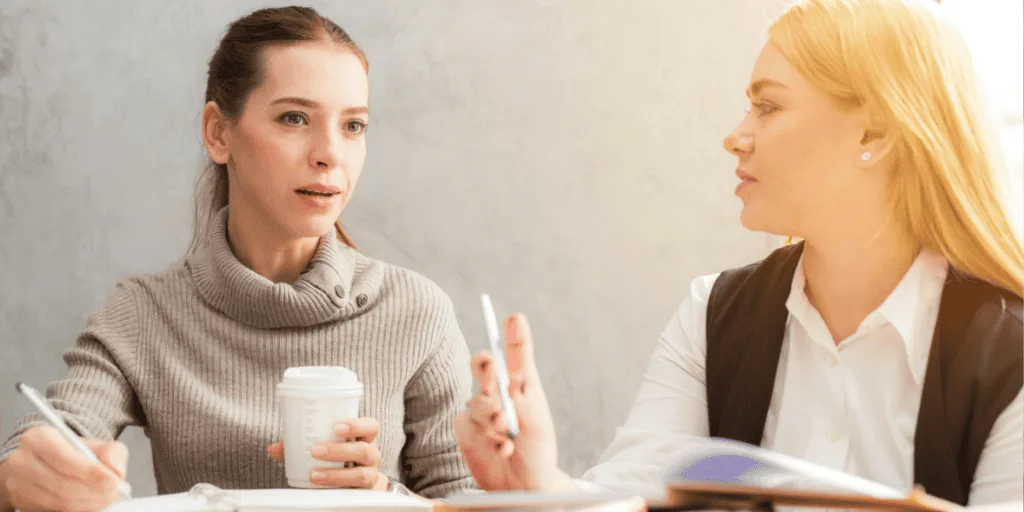 Two women having a focused discussion, symbolizing the role of accountability in staying on track and overcoming procrastination. Ideal for illustrating the power of support and collaboration in productivity.