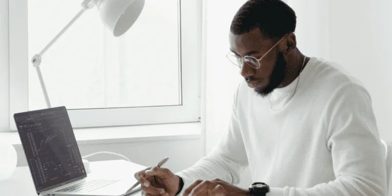 Person working calmly at a minimalist desk with a laptop, calculator, and coffee cup, embodying the concept of healthy striving. The bright, peaceful workspace reflects a balanced approach to productivity and well-being.