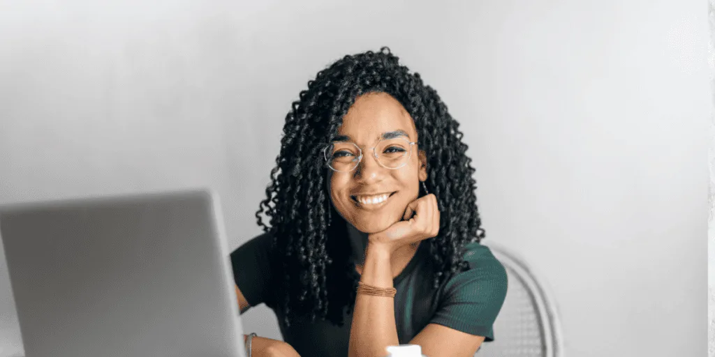 Smiling woman working on a laptop, embodying motivation and productivity—an ideal mindset to overcome procrastination and effectively get things done