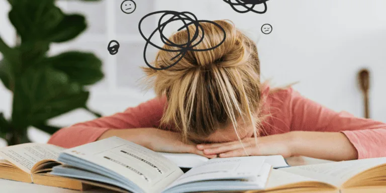 Person with head down on open books, surrounded by scribbled thought bubbles and frowning faces, visually depicting the frustration of being trapped in the perfectionism-procrastination loop