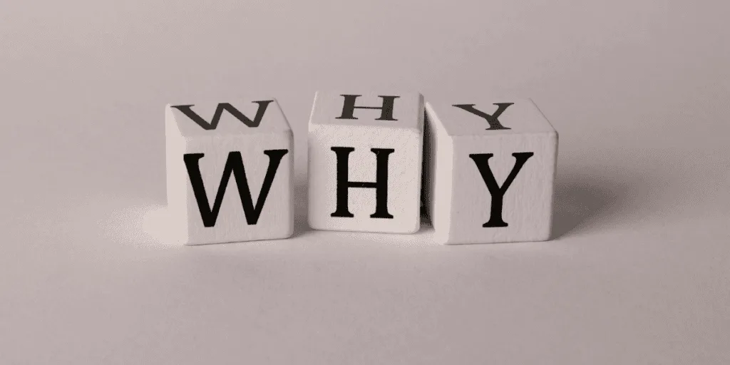 Wooden blocks spelling 'WHY,' symbolizing introspection into reasons behind being stuck in the perfectionism-procrastination loop
