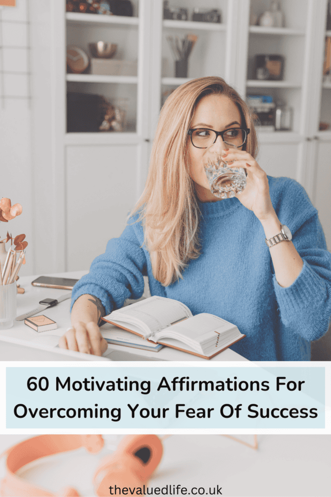 A woman in glasses and a blue sweater drinking water while journaling, with the text '60 Motivating Affirmations for Overcoming Your Fear of Success' displayed below, promoting self-reflection and mindset growth.