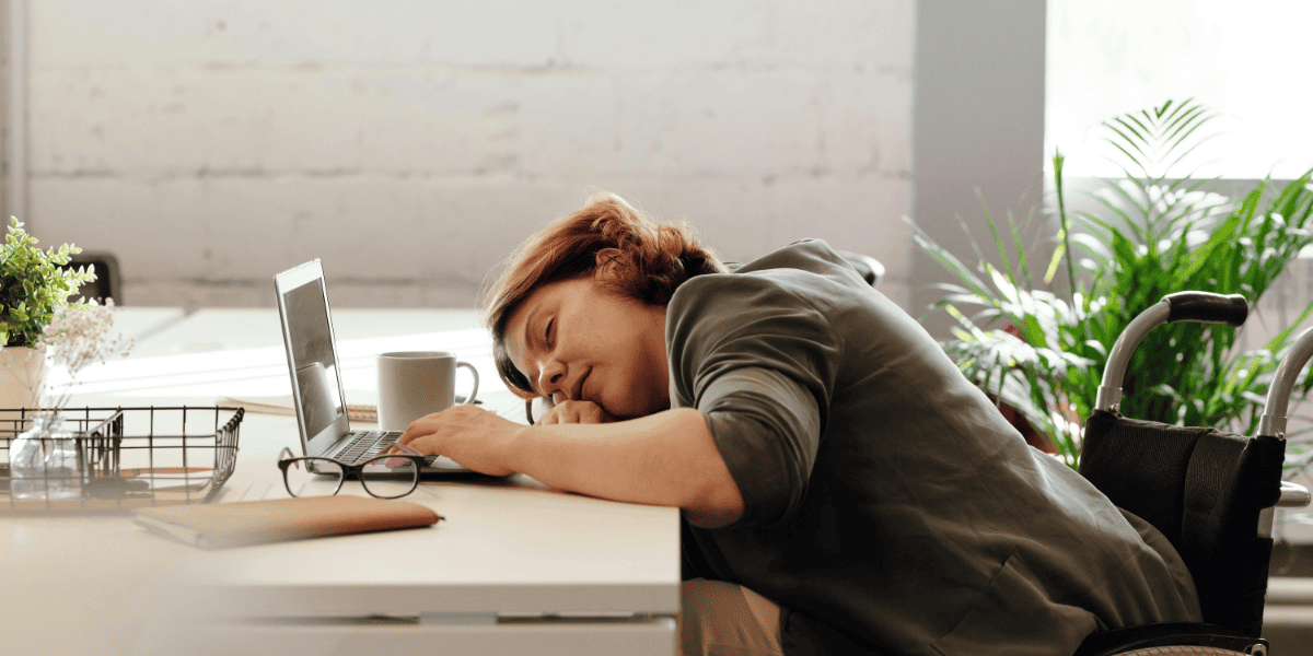 a woman with brain fog with her head on her desk with an open laptop